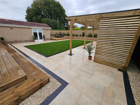 Porcelain-paved garden with a timber pergola and raised sleeper beds