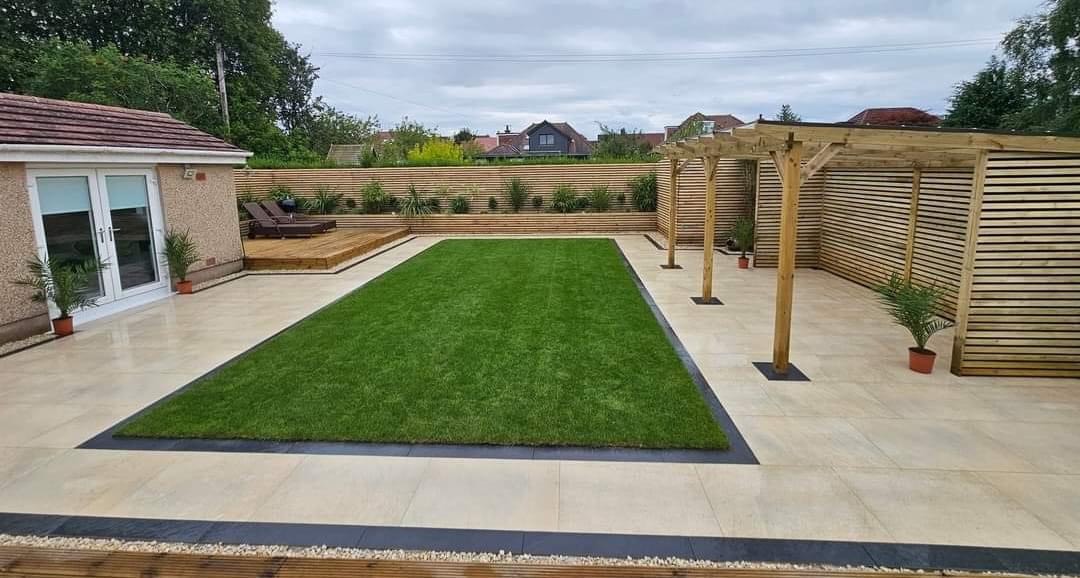 Neat lawn framed by porcelain paving and fencing
